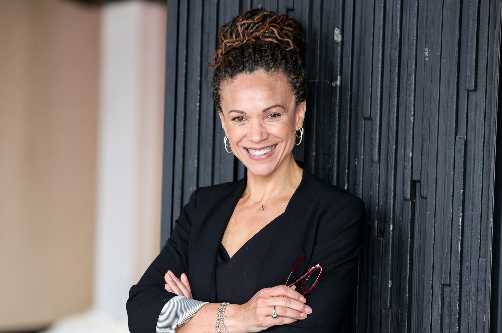 Woman leaning against wall, arms crossed in front of her